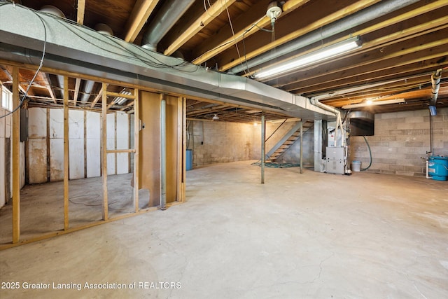 unfinished below grade area featuring heating unit and stairway