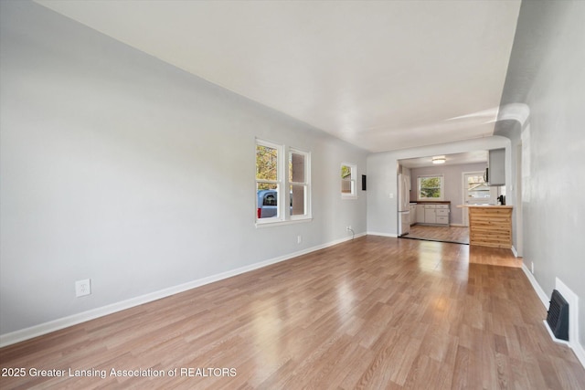 unfurnished living room with visible vents, light wood-style floors, baseboards, and a healthy amount of sunlight