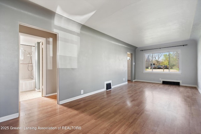 unfurnished living room featuring visible vents, baseboards, and wood finished floors