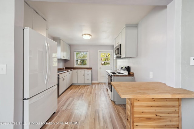 kitchen with white cabinetry, baseboards, light wood-style floors, white appliances, and butcher block countertops
