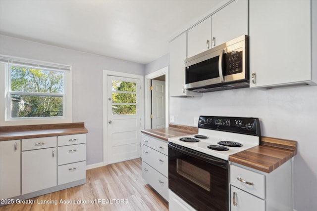kitchen featuring baseboards, electric range oven, stainless steel microwave, white cabinetry, and light wood finished floors