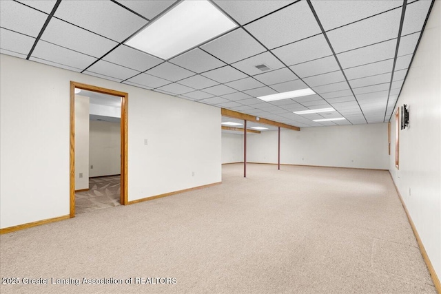 finished below grade area featuring visible vents, carpet flooring, baseboards, and a drop ceiling