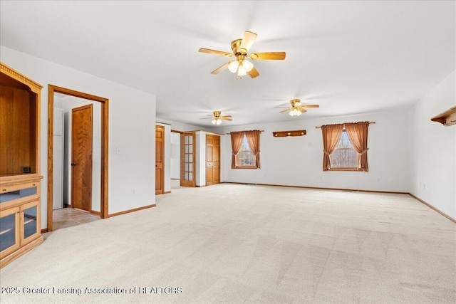 unfurnished living room featuring light colored carpet, a ceiling fan, and baseboards