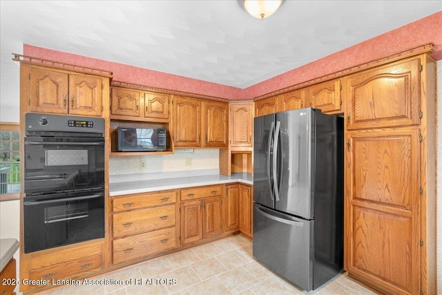kitchen featuring brown cabinetry, light countertops, light tile patterned floors, and black appliances