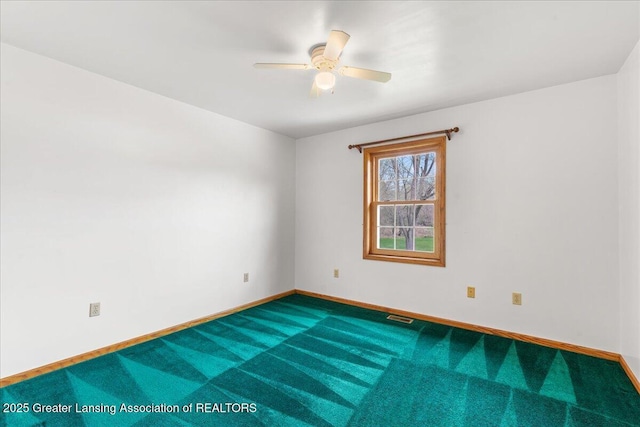 carpeted empty room with visible vents, a ceiling fan, and baseboards