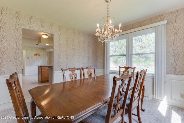 dining space with a decorative wall, wallpapered walls, a notable chandelier, and a wainscoted wall