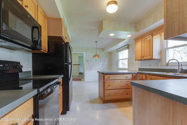 kitchen with a sink, light brown cabinets, a peninsula, wallpapered walls, and black appliances