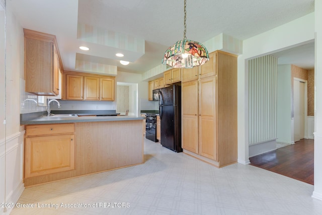 kitchen featuring a sink, light brown cabinets, a peninsula, light floors, and black appliances