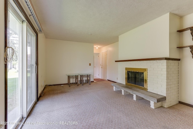 unfurnished living room featuring baseboards, a textured ceiling, carpet, and a brick fireplace