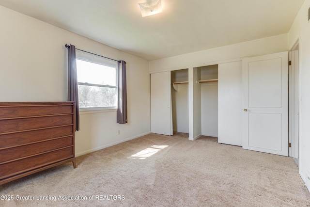 unfurnished bedroom with baseboards, two closets, carpet flooring, and visible vents