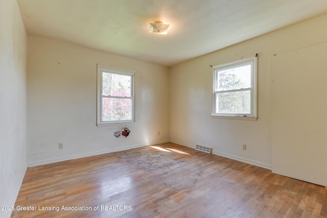 empty room featuring visible vents, light wood-style floors, and baseboards