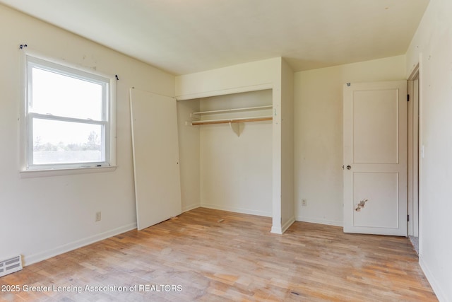 unfurnished bedroom featuring a closet, baseboards, visible vents, and light wood-style floors