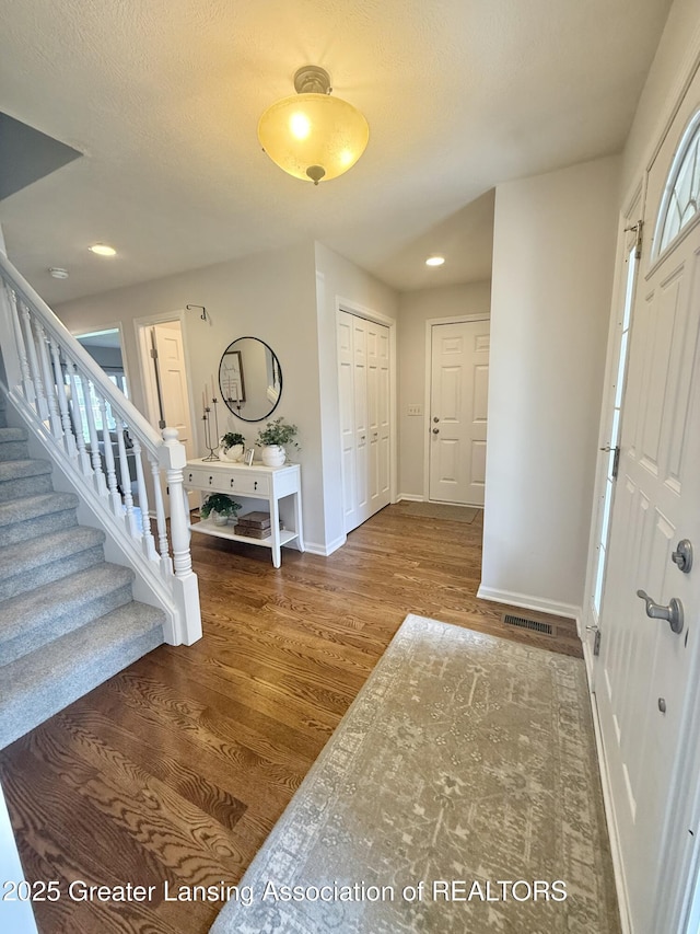 entrance foyer with visible vents, wood finished floors, stairway, baseboards, and recessed lighting