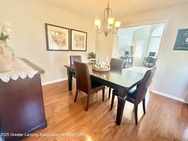 dining space with baseboards, a notable chandelier, and wood finished floors