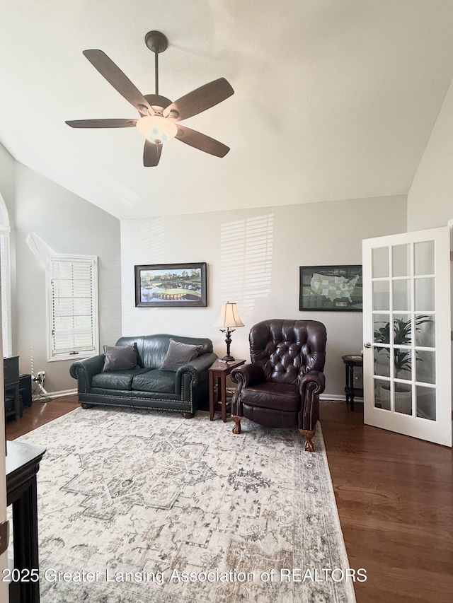 living area with baseboards, dark wood finished floors, ceiling fan, and lofted ceiling