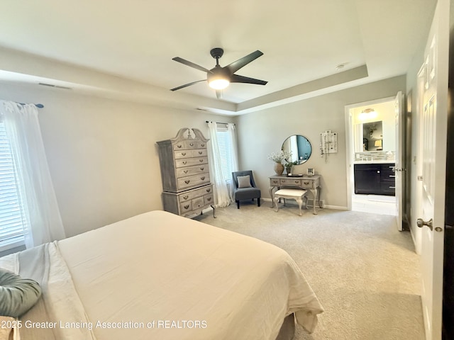 bedroom featuring visible vents, ceiling fan, light colored carpet, connected bathroom, and a raised ceiling