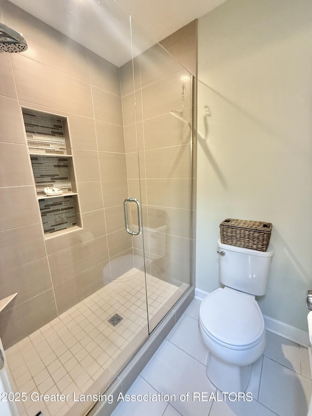 bathroom featuring baseboards, tile patterned flooring, a stall shower, and toilet
