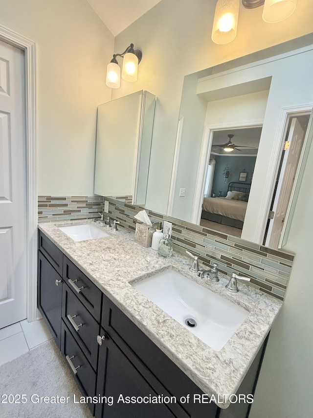 ensuite bathroom featuring ensuite bathroom, a sink, decorative backsplash, and double vanity
