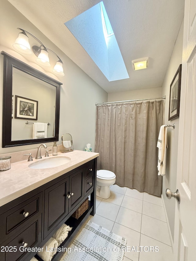 bathroom featuring a textured ceiling, a skylight, tile patterned floors, vanity, and toilet