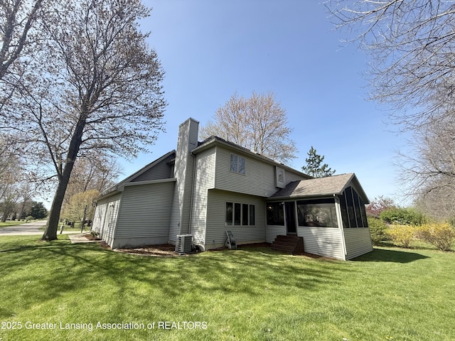 back of property with a yard, a chimney, central AC unit, and a sunroom