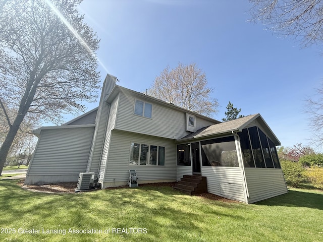 rear view of property with a chimney, a sunroom, cooling unit, a yard, and entry steps