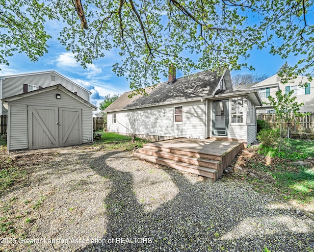 rear view of house with a storage shed, fence, a wooden deck, and a chimney