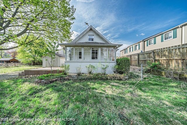 back of property featuring a lawn, fence, and an outdoor structure