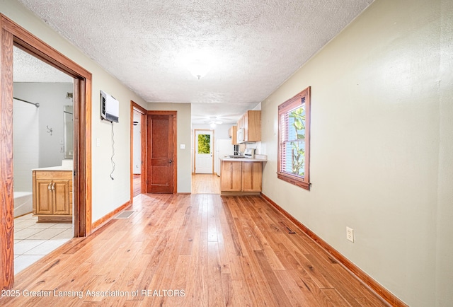 interior space featuring light countertops, a textured ceiling, light wood-style flooring, freestanding refrigerator, and baseboards