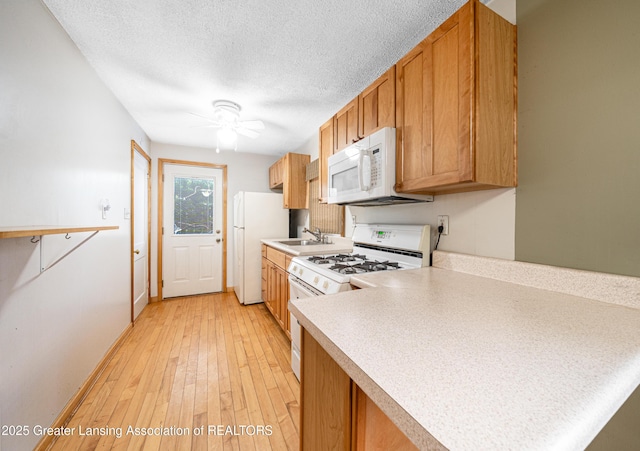 kitchen with ceiling fan, a textured ceiling, light countertops, light wood finished floors, and white appliances