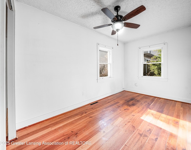 empty room with a textured ceiling, baseboards, and hardwood / wood-style floors