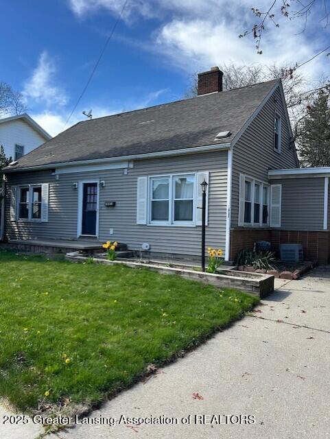 view of front of house featuring central AC, a front yard, and a chimney