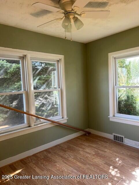 spare room with ceiling fan, baseboards, visible vents, and wood finished floors