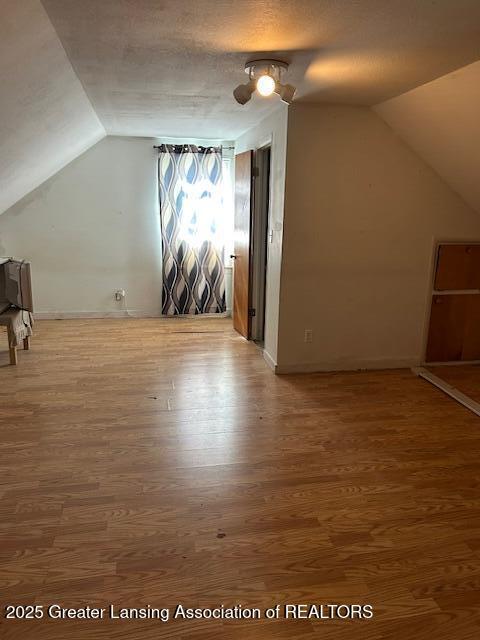 bonus room featuring baseboards, vaulted ceiling, and wood finished floors