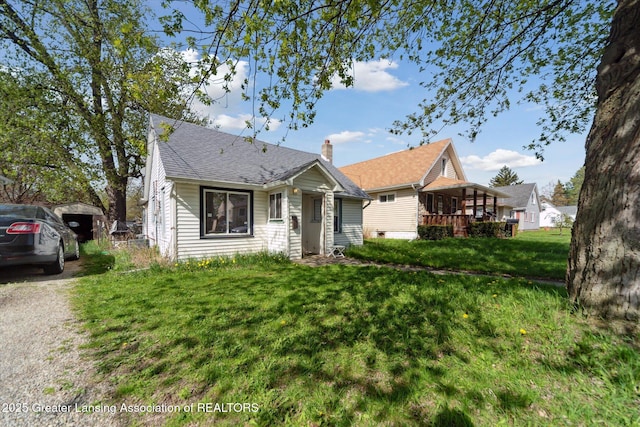 bungalow-style house featuring a chimney, a shingled roof, and a front yard
