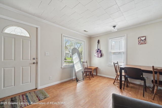 entryway with light wood-style floors, ornamental molding, and baseboards