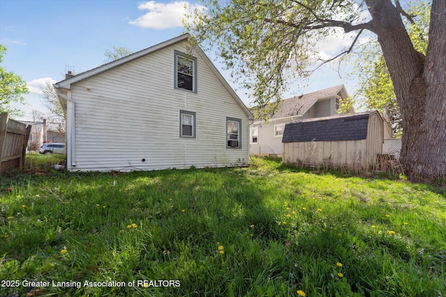 back of property featuring fence, an outbuilding, and a shed