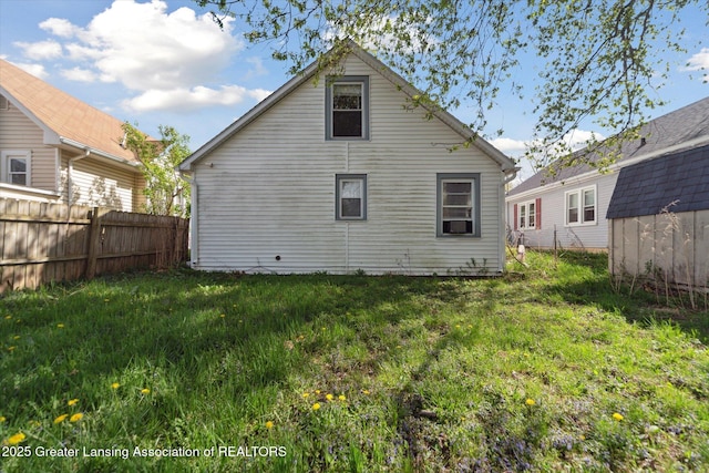 rear view of house with a lawn and fence