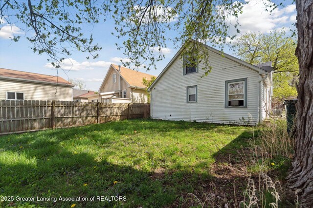 rear view of property with a lawn and fence