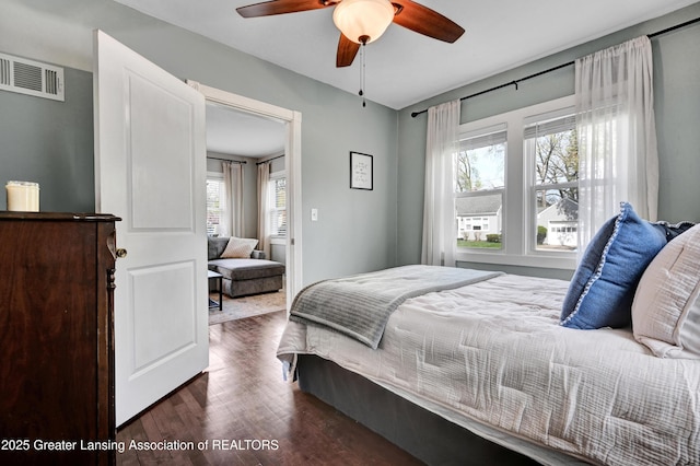bedroom featuring a ceiling fan, visible vents, and dark wood-type flooring