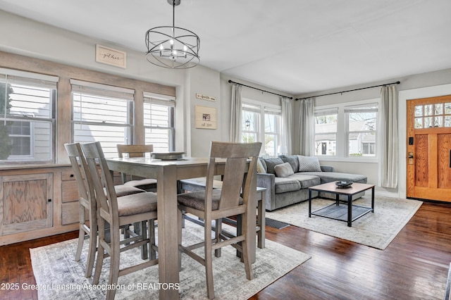 dining space with dark wood-style flooring and an inviting chandelier