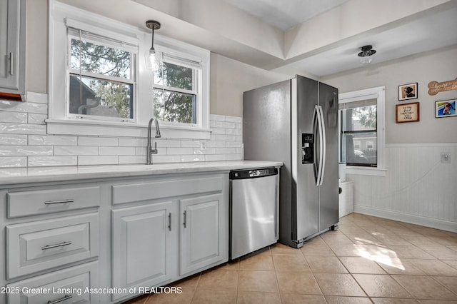 kitchen featuring light countertops, appliances with stainless steel finishes, a healthy amount of sunlight, and tasteful backsplash