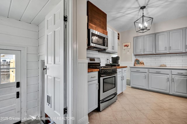 kitchen featuring stainless steel appliances, gray cabinetry, an inviting chandelier, and tasteful backsplash