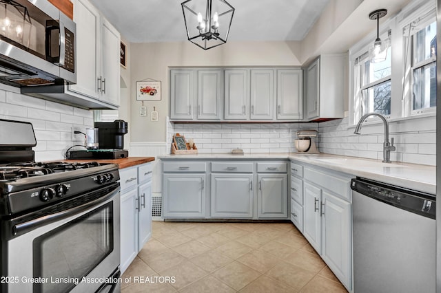 kitchen with stainless steel appliances, gray cabinets, and a sink