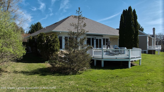 rear view of property featuring a lawn, a shingled roof, a deck, and cooling unit