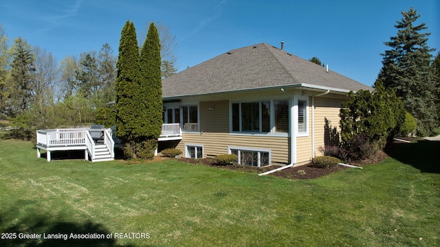 rear view of property featuring a yard, a deck, and roof with shingles