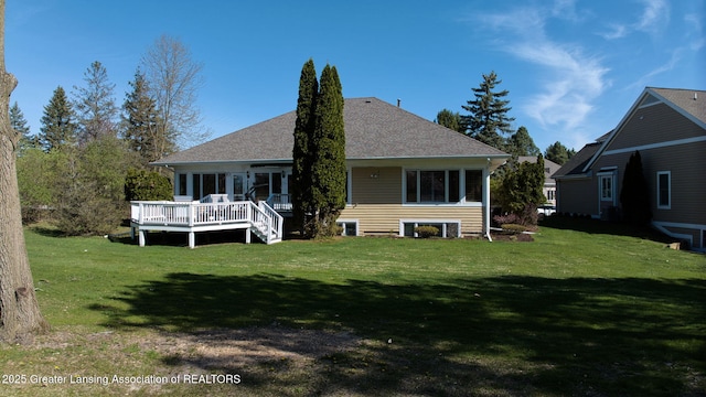back of house featuring a lawn, a wooden deck, and roof with shingles
