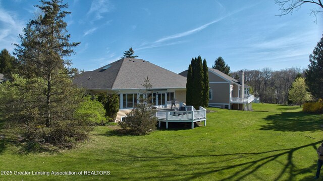 back of property featuring a wooden deck and a yard