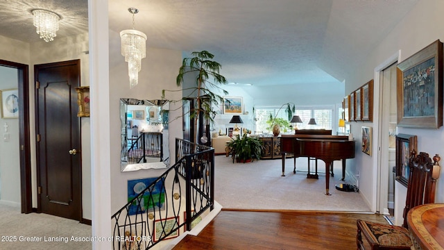 corridor with an inviting chandelier, baseboards, carpet floors, and wood finished floors