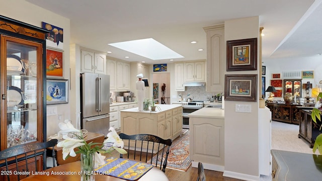 kitchen with light countertops, stainless steel appliances, tasteful backsplash, a kitchen island, and a skylight