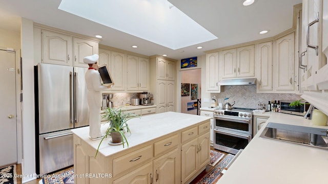kitchen featuring a center island, light countertops, under cabinet range hood, a skylight, and stainless steel appliances